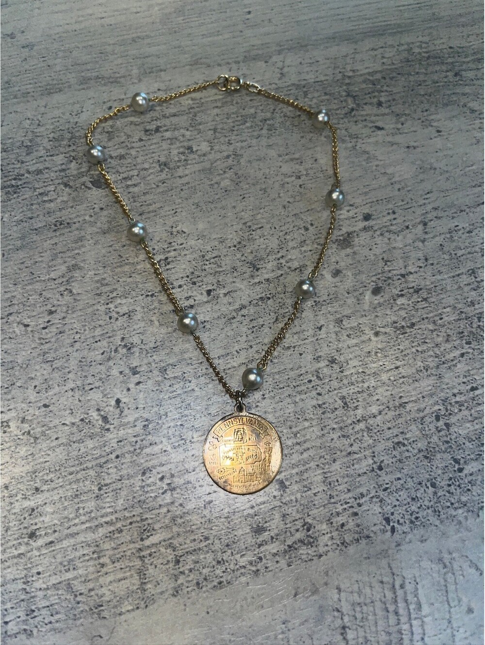 Gold tone pearl station necklace with coin pendant